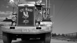 A picture of a semi truck with a customized grill that reads "the little line" and has a bee in the middle. 