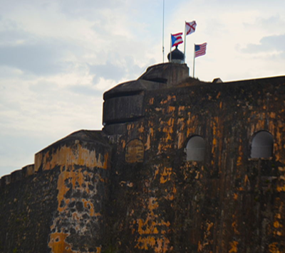 The US flag flies alongside the Puerto Rican flag and the Spanish Cross of Burgundy flag above an observation point installed during World War II at El Morro fort.